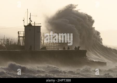 Porthcawl, South Wales, Großbritannien. 18. Februar 2022. Britisches Wetter: Große Wellen stürzen heute Morgen über die Verteidigung des Meeres, als der Sturm Eunice eintrifft. Stockfoto