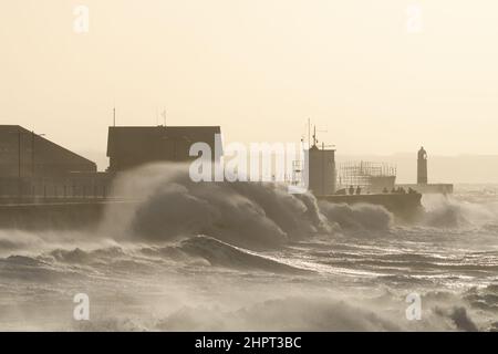 Porthcawl, South Wales, Großbritannien. 18. Februar 2022. Britisches Wetter: Große Wellen stürzen heute Morgen über die Verteidigung des Meeres, als der Sturm Eunice eintrifft. Stockfoto