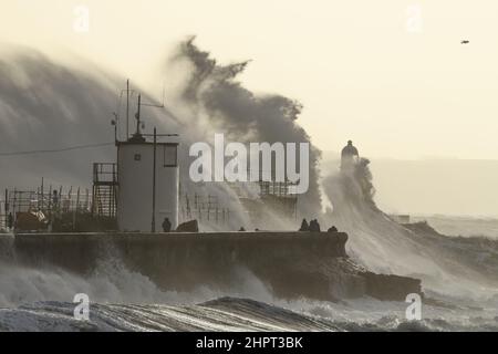 Porthcawl, South Wales, Großbritannien. 18. Februar 2022. Britisches Wetter: Große Wellen stürzen heute Morgen über die Verteidigung des Meeres, als der Sturm Eunice eintrifft. Stockfoto