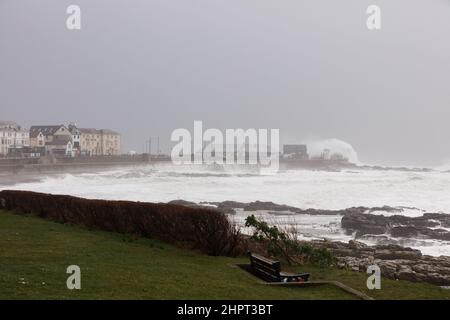 Porthcawl, South Wales, Großbritannien. 18. Februar 2022. Britisches Wetter: Große Wellen stürzen heute Morgen über die Verteidigung des Meeres, als der Sturm Eunice eintrifft. Stockfoto