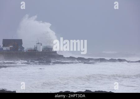 Porthcawl, South Wales, Großbritannien. 18. Februar 2022. Britisches Wetter: Große Wellen stürzen heute Morgen über die Verteidigung des Meeres, als der Sturm Eunice eintrifft. Stockfoto