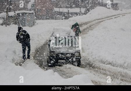 Srinagar, Indien. 23rd. Februar 2022. Menschen gehen am 23. Februar 2022 in Srinagar, Kaschmir, Indien, durch eine schneebedeckte Straße, Aufgrund von starkem Schneefall wurden die meisten der Flüge gestrichen und der Srinagar-Jammu National Highway wurde für Autofahrer gesperrt. (Fotos von Kamran Raashid Bhat/INA Photo Agency/Sipa USA) Quelle: SIPA USA/Alamy Live News Stockfoto