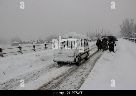 Srinagar, Indien. 23rd. Februar 2022. Menschen gehen am 23. Februar 2022 in Srinagar, Kaschmir, Indien, durch eine schneebedeckte Straße, Aufgrund von starkem Schneefall wurden die meisten der Flüge gestrichen und der Srinagar-Jammu National Highway wurde für Autofahrer gesperrt. (Fotos von Kamran Raashid Bhat/INA Photo Agency/Sipa USA) Quelle: SIPA USA/Alamy Live News Stockfoto