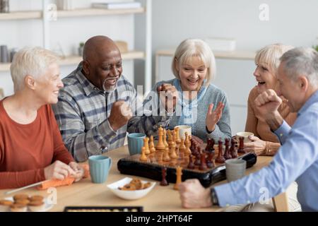 Emotionale, multiethnische Gruppe älterer Menschen, die Schach spielen Stockfoto