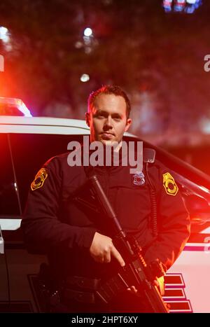 Einige Situationen erfordern mehr Kraft als andere. Beschnittenes Porträt eines hübschen jungen Polizisten, der mit seinem Sturmgewehr auf der Patrouille steht. Stockfoto