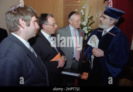 Der Oberrabbiner Jonathan Sacks war Ehrengast bei der Feier des 25th. Jahrestages der hebräischen Kongregation Solihull. Bei seinem Besuch traf er Kinder im Salon einer Familie aus der Gemeinde. Informell spricht er mit jungen jüdischen Kindern über ihre Arbeit im Cheder (Klassenzimmer) der Synagoge, blickt Gemeindepfarr Rabbi Yehuda Pink hin. Er sprach während eines Gedenkgottesdienstes am 27th. Oktober 2002.der Bürgermeister von Solihull Cllr. Kate Wild war dabei und erhielt einen Strauß von der Cheder-Schülerin, 13 Jahre alt, Zipporah Gershon Stockfoto