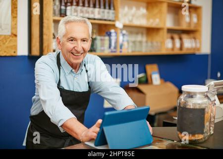 Sein Service ist immer sehr gastfreundlich. Aufnahme eines älteren Mannes, der in einem Café arbeitet. Stockfoto