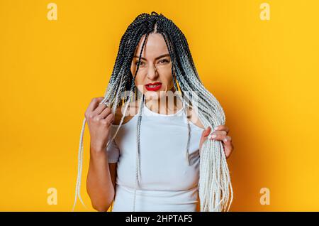 Wütende Frau mit Dreadlocks. Roter Lippenstift. Hände halten Dreadlocks. Stockfoto