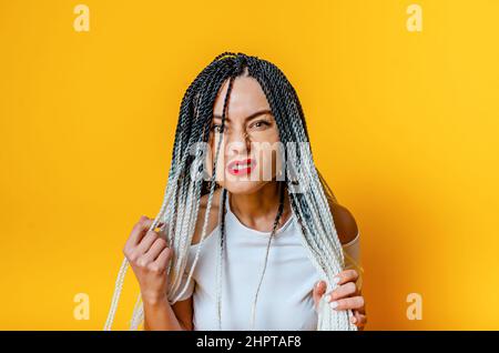 Porträt einer wütenden Frau mit Dreadlocks. Roter Lippenstift. Hände halten Dreadlocks. Stockfoto