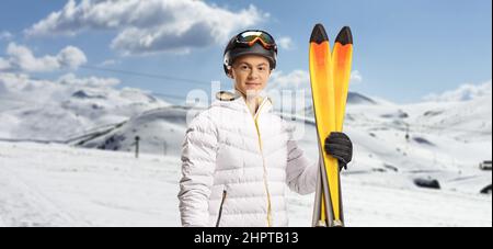 Kerl hält ein Paar Skier und posiert auf einem Berg Stockfoto