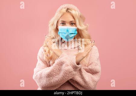 Die Dame trägt eine medizinische Gesichtsmaske und zeigt mit gekreuzten Armen eine Stop-Geste und sagt Nein zur Coronavirus-Quarantäne Stockfoto