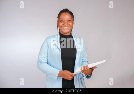 Junge afrikanische Dame lächelt auf der Kamera mit einigen Dokumenten in ihren Händen. Stockfoto