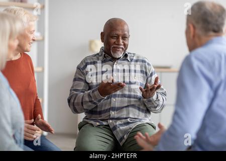 Fröhlicher afroamerikanischer älterer Mann, der sich mit einem Trainer untersprach Stockfoto