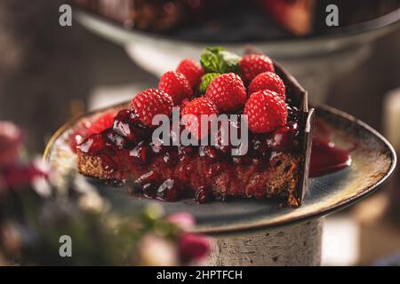 Scheibe Schokoladenkuchen mit Kirschsoße und mit frischen Himbeeren dekoriert Stockfoto