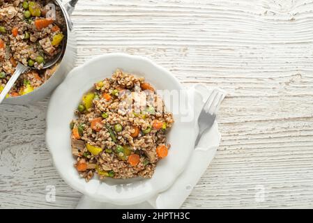 Buchweizengericht mit Huhn und Gemüse auf dem Teller auf Holztisch serviert Stockfoto