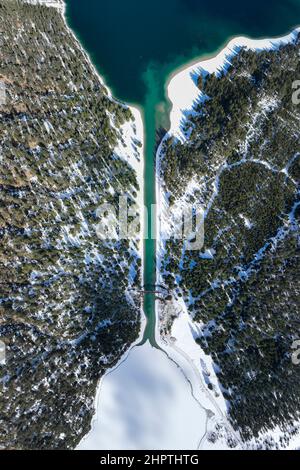 Blick aus der Vogelperspektive auf den Kanal mit Holzbrücke zwischen plansee und heiterwanger See im Winter mit teilweise gefrorenem Wasser Stockfoto