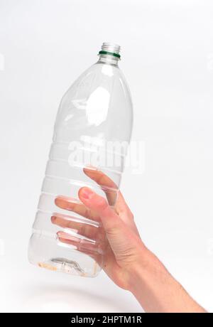 Hand hält eine Einweg-Kunststoff-Getränkeflasche bereit für das Recycling vor einem weißen Hintergrund fotografiert. Stockfoto
