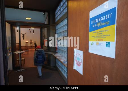 Berlin, Deutschland. 23rd. Februar 2022. Eine Einladung zum Gebet für den Frieden in der Ukraine hängt am Eingang der Michaelskirche in Berlin-Kreuberg. Die Einladung erfolgte durch den Diözesanrat der Katholiken in der Erzdiözese Berlin gemeinsam mit dem Bund Deutscher Katholischer Jugend (BDKJ) Diözesanverband Berlin und der internationalen katholischen Friedensbewegung 'Pax christi' Berlin. Quelle: Jörg Carstensen/dpa/Alamy Live News Stockfoto