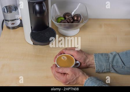 Nahaufnahme von männlichen Händen, die einen Becher mit gegossener Kaffeepulver aus der Kaffeemaschine halten. Schweden. Stockfoto
