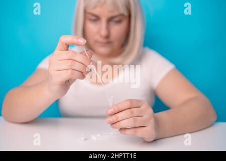 Frau Hände machen Coronavirus-Test und Rühren Tupfer in Reagenz. Medizin, Quarantäne und Pandemiekonzept Stockfoto