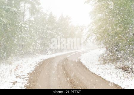 Früher Schneefall auf einer ländlichen nördlichen Straße. Stockfoto
