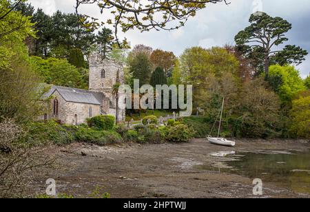 Segeln nach St. Just in Roesland: Eine kleine Pfarrkirche an der Südküste, umgeben von einem kleinen Friedhof und Gärten. Am Strand steht ein Segelboot. Stockfoto