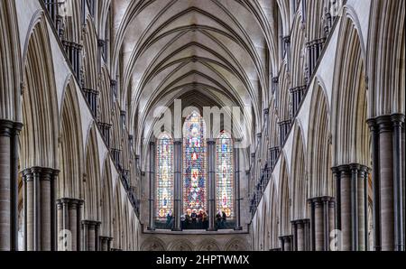 Säulen und Heckfenster in Salisbury: Die Decke und die Heckscheibe der Kathedrale von Salisbury. Unten am Fenster hält eine Reisegruppe an. Stockfoto