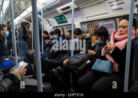 London, Großbritannien. 23. Februar 2022. Pendler in der U-Bahn zur Hauptverkehrszeit auf der Jubilee-Linie. Die britische Regierung hat angekündigt, dass alle Covid-19-Beschränkungen ab dem 24. Februar gelockert werden. Transport for London (TFL) „empfiehlt dringend, dass Passagiere eine Gesichtsbedeckung tragen, wenn sie dies können“, obwohl das Tragen einer Gesichtsbedeckung nicht mehr zur Beförderung gehört. Kredit: Stephen Chung / Alamy Live Nachrichten Stockfoto