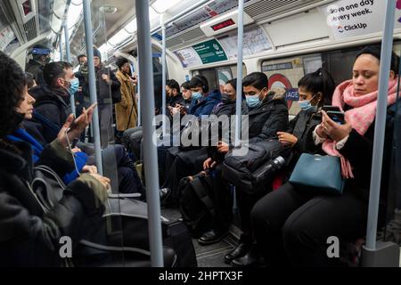 London, Großbritannien. 23. Februar 2022. Pendler in der U-Bahn zur Hauptverkehrszeit auf der Jubilee-Linie. Die britische Regierung hat angekündigt, dass alle Covid-19-Beschränkungen ab dem 24. Februar gelockert werden. Transport for London (TFL) „empfiehlt dringend, dass Passagiere eine Gesichtsbedeckung tragen, wenn sie dies können“, obwohl das Tragen einer Gesichtsbedeckung nicht mehr zur Beförderung gehört. Kredit: Stephen Chung / Alamy Live Nachrichten Stockfoto