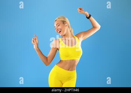 Lächelnde Junge Frau In Sportswear Musik Hören Und Tanzen Stockfoto