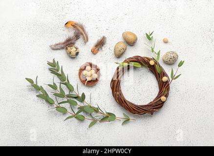 Komposition mit Kranz, Eukalyptuszweigen, Federn und Ostereiern auf hellem Hintergrund Stockfoto