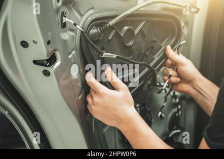 Der Kundendienstmitarbeiter demontiert die Autotür für Reparaturen aus nächster Nähe. Stockfoto