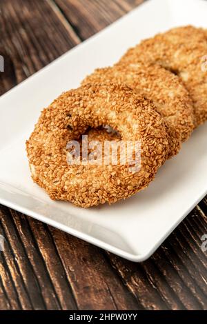 Türkischer Name Kandil simidi mit Tee daneben auf Holztisch. Türkischer Bagel mit Sesamsamen oder salzigen Ringkeksen. Stockfoto