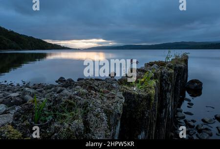 Blick auf Loch Rannoch über den Pier am Ostufer, während die Sonne über den Bergen in der Ferne untergeht, Rannoch, Schottland, Vereinigtes Königreich. Stockfoto