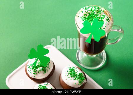 Irischer Kaffee und spezielle Cupcakes für den Happy St. Patricks Day auf grünem Hintergrund. Nahaufnahme. Speicherplatz kopieren. Stockfoto