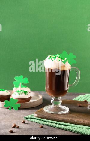 Irischer Kaffee in grüner Tasse und spezielle Cupcakes für den St. Patricks Day auf grünem Hintergrund. Alles gute zum St. patricks Day. Stockfoto