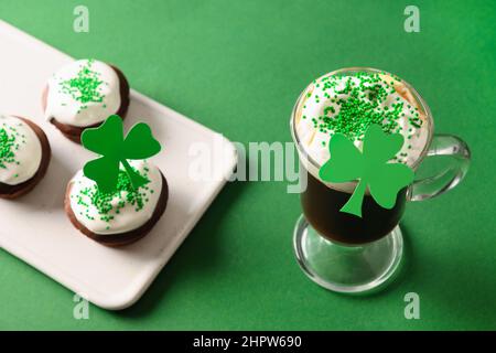 Irischer Kaffee und spezielle Cupcakes für den Happy St. Patricks Day auf grünem Hintergrund. Nahaufnahme. Stockfoto