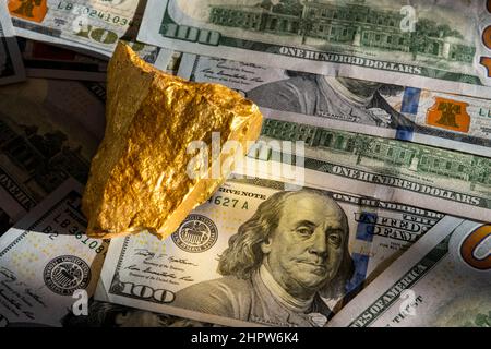 Natürliche goldene Nuggets auf Hunderten US-Dollar-Scheinen. Investieren Sie in echtes Gold als Goldbarren. Nahaufnahme Gold finanzieren Vermögen oder Ersparnisse. Finanzkonzept Stockfoto