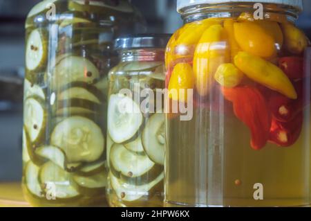 Gelbe Paprika und Gurke in Dosen in einem Glas auf Holzgrund, natürliches Licht. Stockfoto