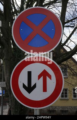 Rot-blaues deutsches Verkehrsschild 283 „No-Stop“ auf rotem, weißem und schwarzem deutschen Verkehrsschild 208 „Priorität für Gegenverkehr“ Stockfoto