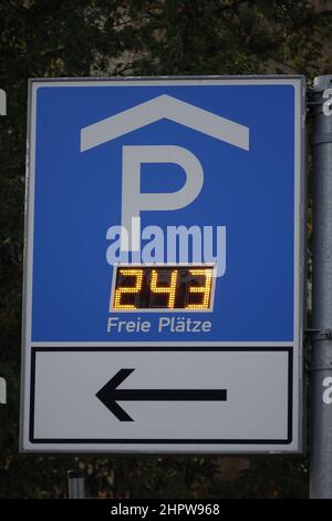 Blaues und weißes Wegweiser zum Parkhaus (links) und zum Parkplatz (rechts), das die Anzahl der freien Plätze elektronisch angibt Stockfoto