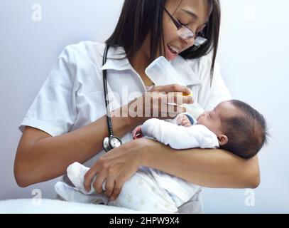 Einen fürsorglichen Beitrag zur Gesellschaft leisten. Aufnahme eines Arztes, der einem Säugling mit Gaumenspalte eine Formel gibt. Stockfoto