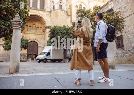 Foto in voller Länge von Touristen, die beim Gehen Fotos vom Gebäude machen Stockfoto