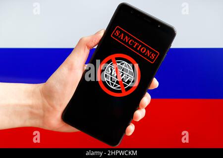 Ukraine, Kiew - Februar, 23 2022: Handgriff mit SWIFT-Finanzsystem-Logo unter rotem Verbotsschild mit russischer Flagge im Hintergrund. Sa Stockfoto