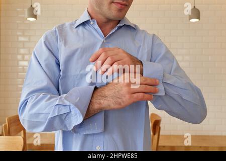 Der Mann befestigt den Manschettenknauf auf dem Ärmel seines Hemdes. Der Bräutigam befestigt einen Knopf auf dem Ärmel seines Hemdes Stockfoto