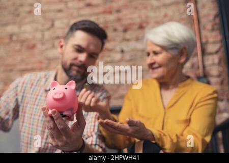 Der kaukasische Geschäftsmann überraschte die Art und Weise, wie seine ältere Mutter ihr Geld spart. Hochwertige Fotos Stockfoto