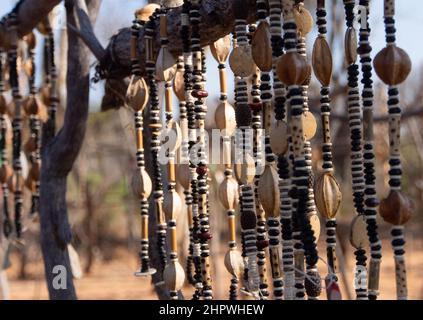 Nahaufnahme von Schnüren afrikanischer Halsketten aus Perlen und Samen, die auf einem Outdoor-Markt in Namibia ausgestellt werden. Hintergrund unscharf oder unscharf Stockfoto