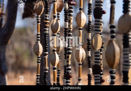 Nahaufnahme von Schnüren afrikanischer Halsketten aus Perlen und Samen, die auf einem Outdoor-Markt in Namibia ausgestellt werden. Hintergrund unscharf oder unscharf Stockfoto