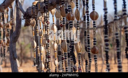 Nahaufnahme von Schnüren afrikanischer Halsketten aus Perlen und Samen, die auf einem Outdoor-Markt in Namibia ausgestellt werden. Hintergrund unscharf oder unscharf Stockfoto