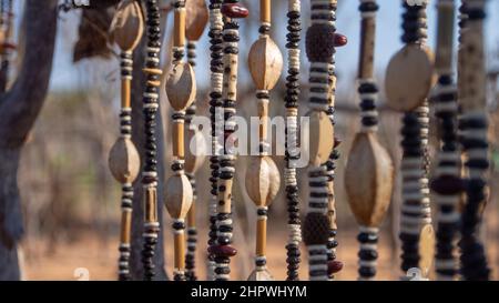 Nahaufnahme von Schnüren afrikanischer Halsketten aus Perlen und Samen, die auf einem Outdoor-Markt in Namibia ausgestellt werden. Hintergrund unscharf oder unscharf Stockfoto